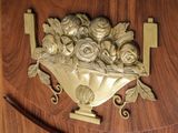 a gold vase with roses on it on a wooden wall
