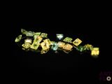 some green and yellow diamonds are scattered on a black surface