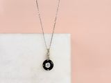 a black and white diamond pendant on a white marble slab