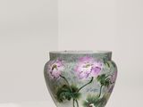un vase orné de fleurs peintes, posé sur un socle blanc