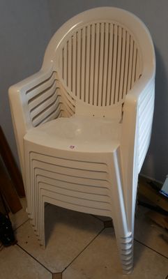 une chaise en plastique blanche posée sur un sol carrelé