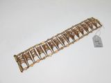 gros plan d'un bracelet en or sur une surface blanche