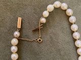 a close up of a white pearl necklace with a gold clasp