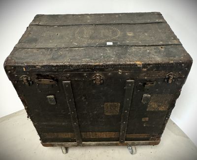 an old black trunk sitting on a white surface