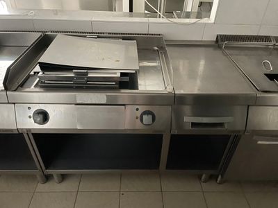 plan de travail en acier inoxydable dans une cuisine professionnelle, équipé d'un évier et d'une cuisinière