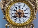 a gold clock with a white face on a table
