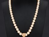 un collier en perles et en or avec un pendentif, porté par un mannequin