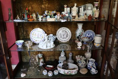 une vitrine sur laquelle sont disposées de nombreuses pièces de vaisselle en porcelaine