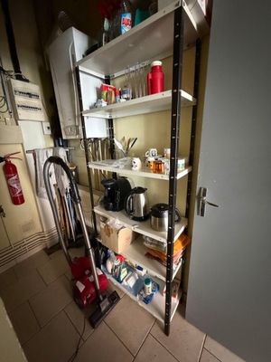 une petite cuisine dont les étagères sont encombrées