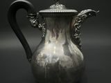 une théière en argent avec une anse noire sur fond noir