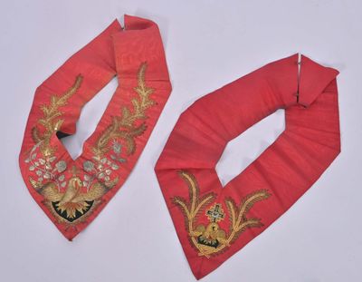 deux morceaux de tissu rouge ornés de broderies dorées sur fond blanc