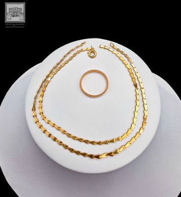 a white plate with a gold necklace and a gold ring on it
