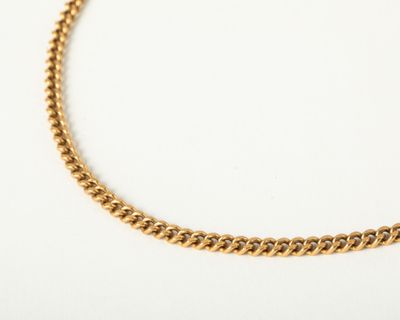 a close up of a gold chain necklace on a white surface