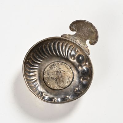 a silver spoon with a coin in it on a white surface
