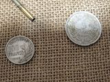 two coins and a bullet on a burlock cloth