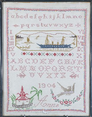 une photo d'une broderie au point de croix représentant un bateau dans une bouteille