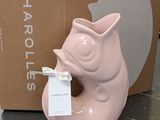a pink cat shaped vase with a tag in front of a cardboard box