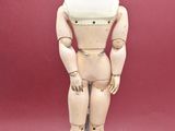 a wooden mannequin standing on a white base