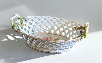 a white basket with flowers on it sitting on a table