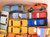 many toy cars in a cardboard box on the floor