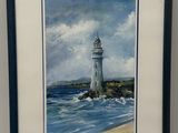 un tableau représentant un phare sur une plage rocheuse, dans un cadre noir