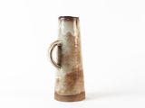 a brown and white vase with a handle on a white background