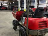 a red tractor parked in a warehouse with other vehicles