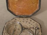 a small silver pocket with a clock inside of it