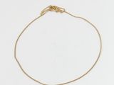un bracelet à chaîne en or avec une breloque en forme de cœur sur fond blanc