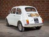 a small white car that is parked in front of a brick wall