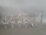 five wine glasses and a pitcher on a table
