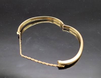 une image représentant un bracelet en or posé sur une surface noire