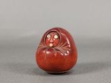 une petite figurine rouge et blanche posée sur une table