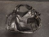 a black purse sitting on the ground on the ground