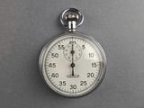 a close up of a silver stopwatch on a gray surface