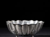 a silver bowl on a stand on a black surface