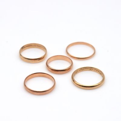 five gold wedding rings on a white background