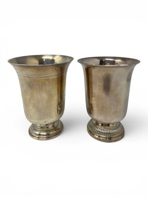 two silver vases sitting next to each other on a white surface
