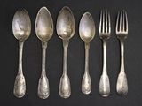 six cuillères en argent et une fourchette posées sur un fond noir