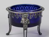 un bol en verre bleu posé sur un socle orné d'une tête de lion