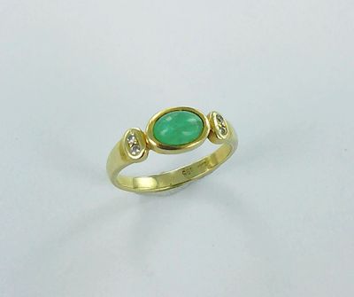 a close up of a gold ring with a green stone