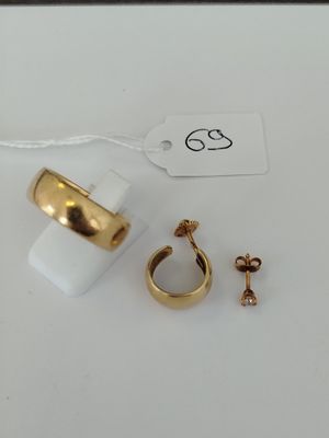 two gold rings and a pair of earrings on a white surface