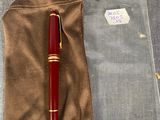un stylo rouge posé sur un sac marron
