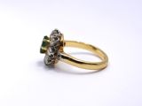 a close up of a gold ring with a diamond and emerald