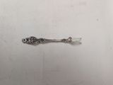 a silver spoon with a flower on it on a white surface