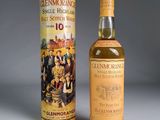 une vieille bouteille de whisky écossais Glenmore de 10 ans, posée à côté d'une boîte métallique