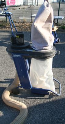un sac posé sur un chariot, auquel est raccordé un tuyau