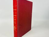 un vieux livre rouge posé sur une table blanche