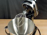 a metal bowl with a whisk inside of it on a wooden table