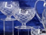 four wine glasses and a pitcher sitting on a table